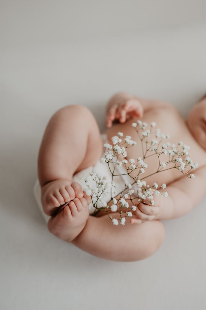 A close-up of a baby holding delicate flowers, showcasing purity and new life.
